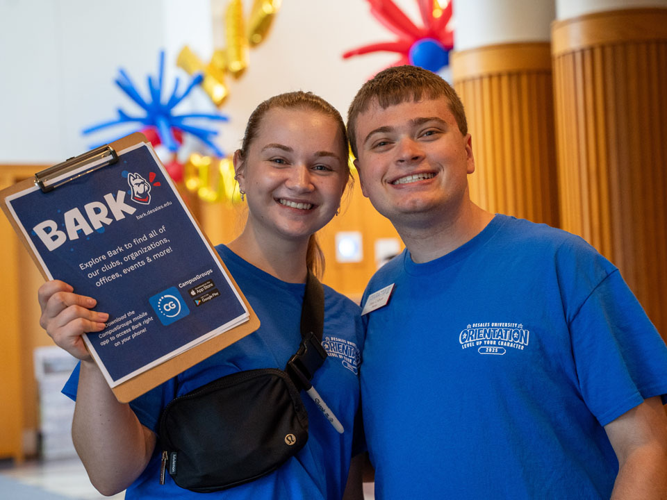 two students smiling during first-year move in to holding a clipboard with information about BARK