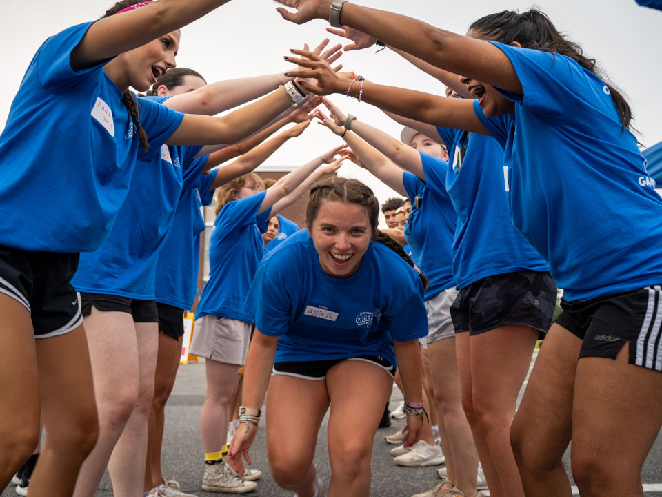 a smiling student running through a student tunnel during move in day