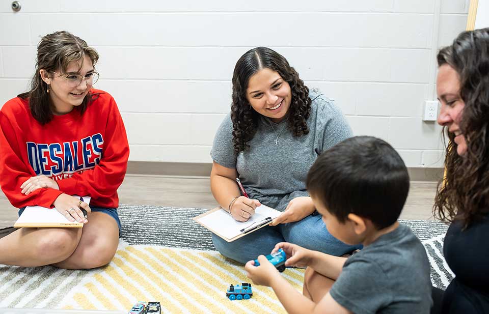 students providing speech therapy to a young boy