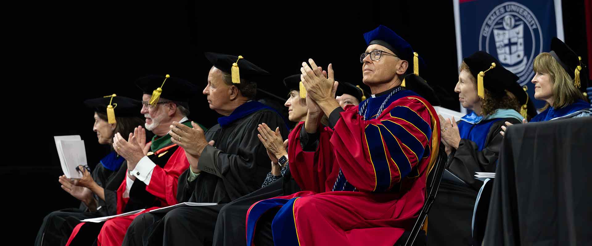 Father Jim Greenfield seated at a commencement ceremony