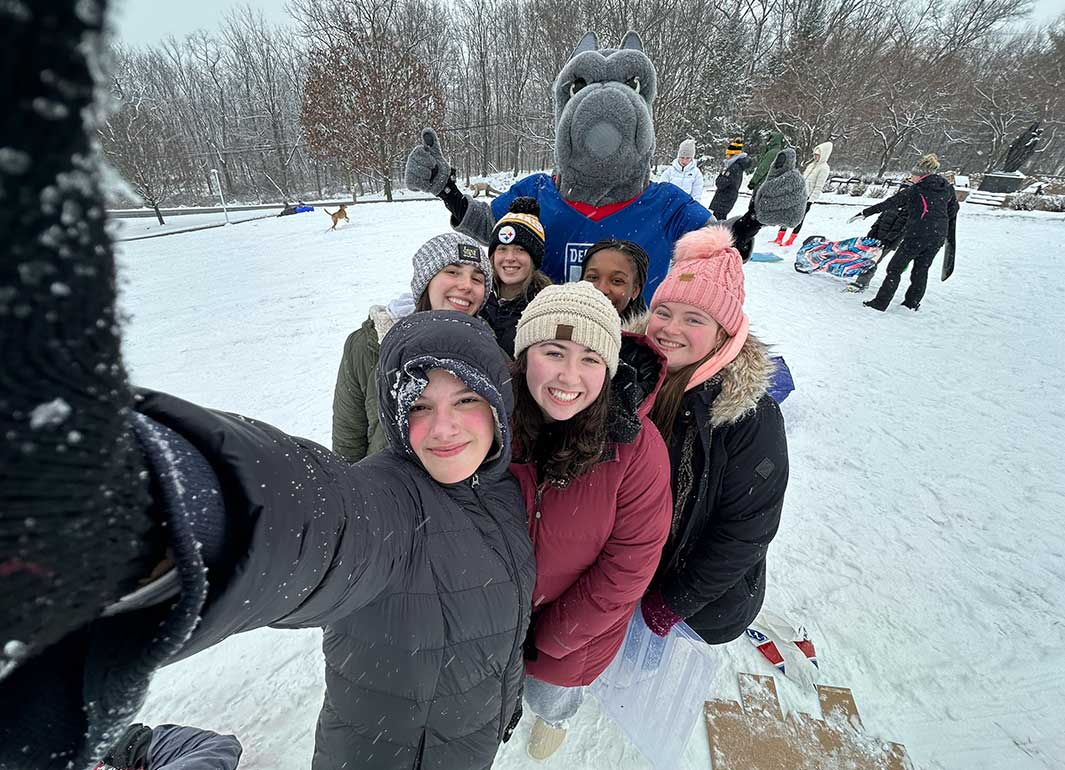 students on the sledding hill with the mascot