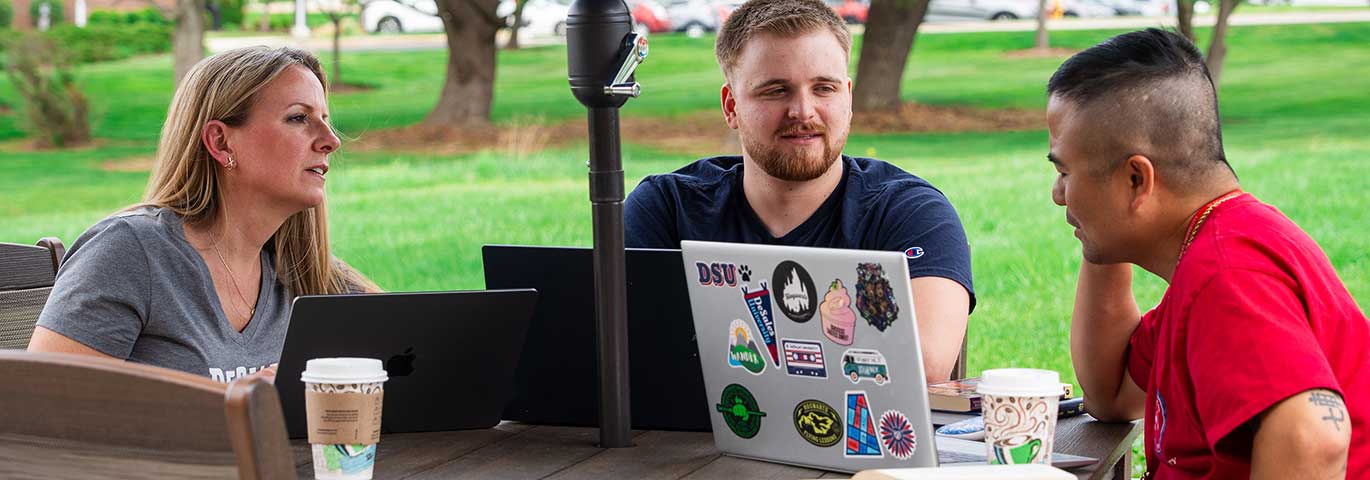 students with laptops at picnic table