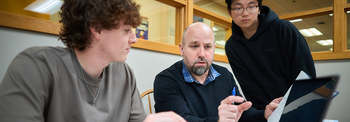 students talking with professor at computer