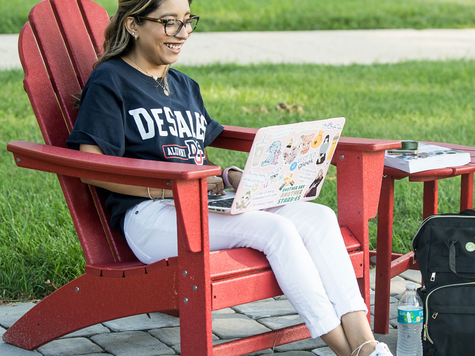 student outside working on laptop