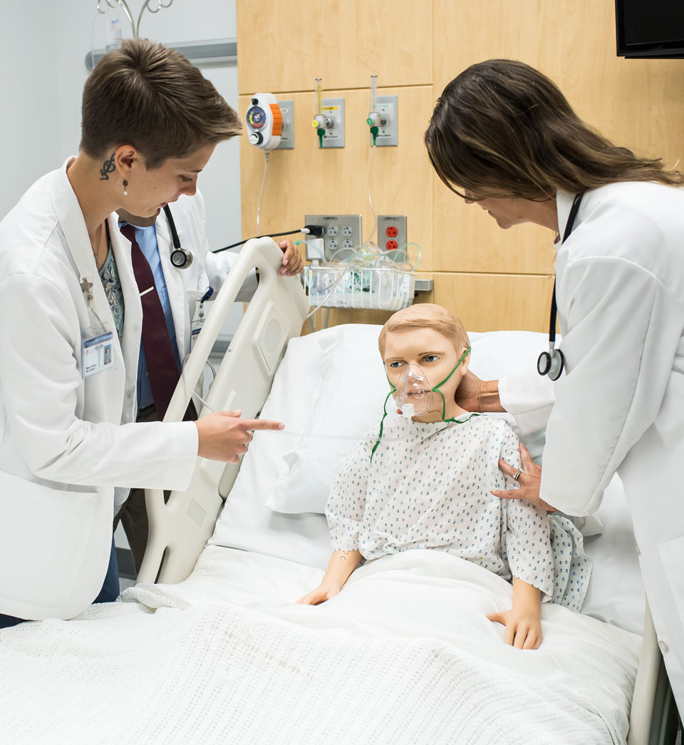 student looking at a patient mannequin