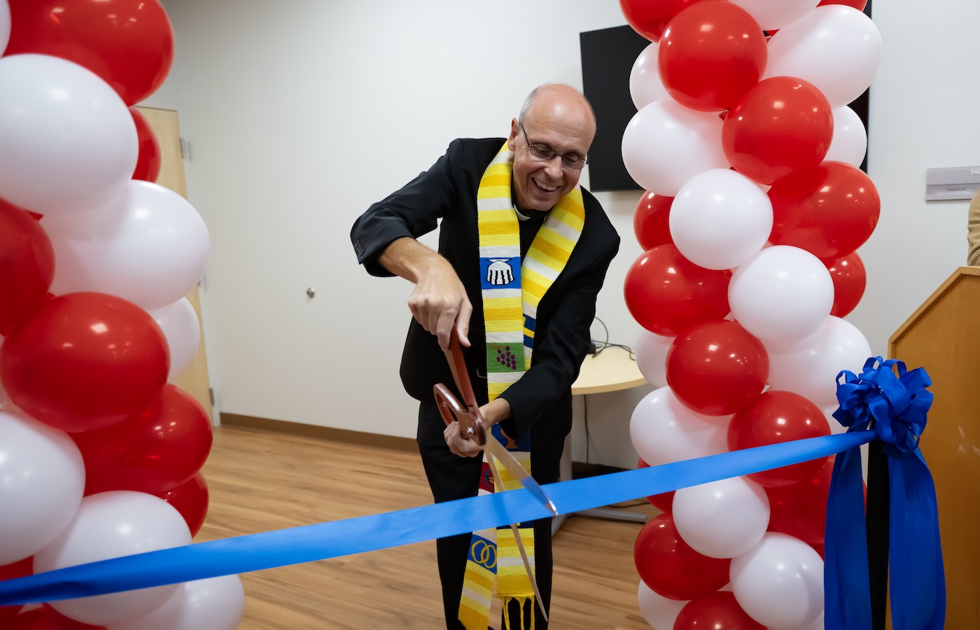 Fr. Jim Greenfield cutting a ribbon