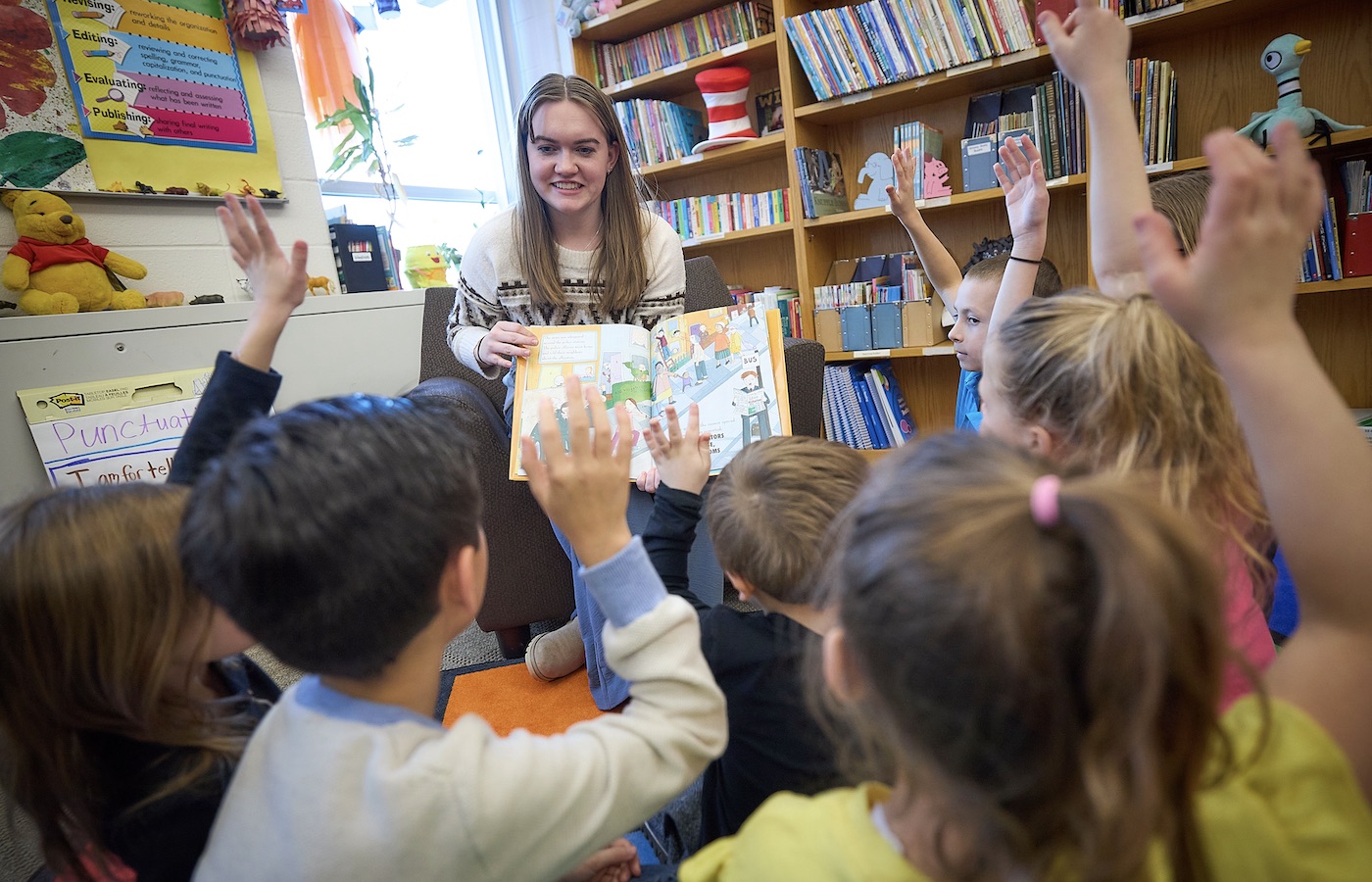 Girl reading a book to children